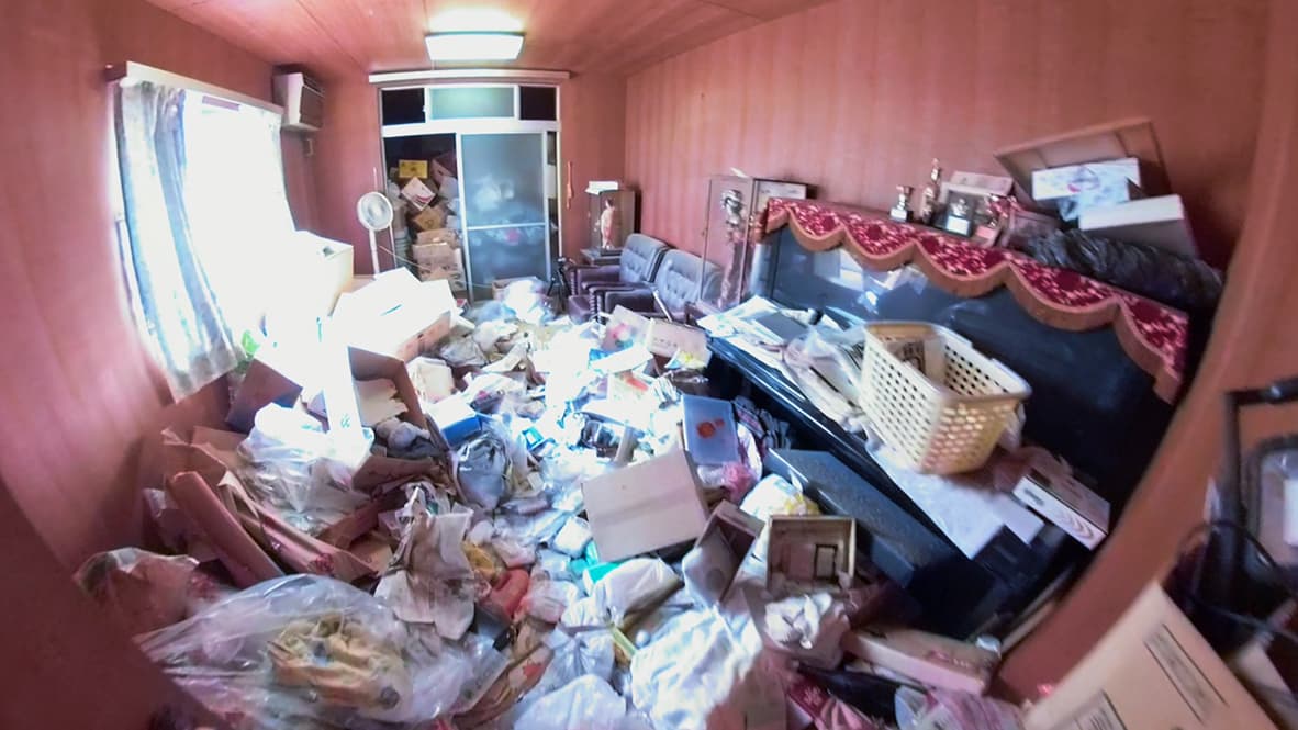 「ゴミ屋敷になってしまった実家の片付け」ピアノのある洋室のビフォー写真（床が見えないほどモノがあふれている）