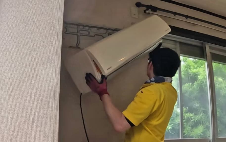 実家の片付け中、スタッフがエアコンを丁寧に取り外している様子
