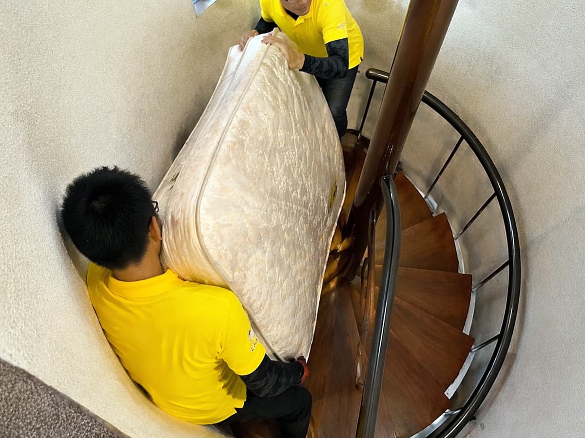螺旋階段でマットレスを慎重に運び出している作業の様子