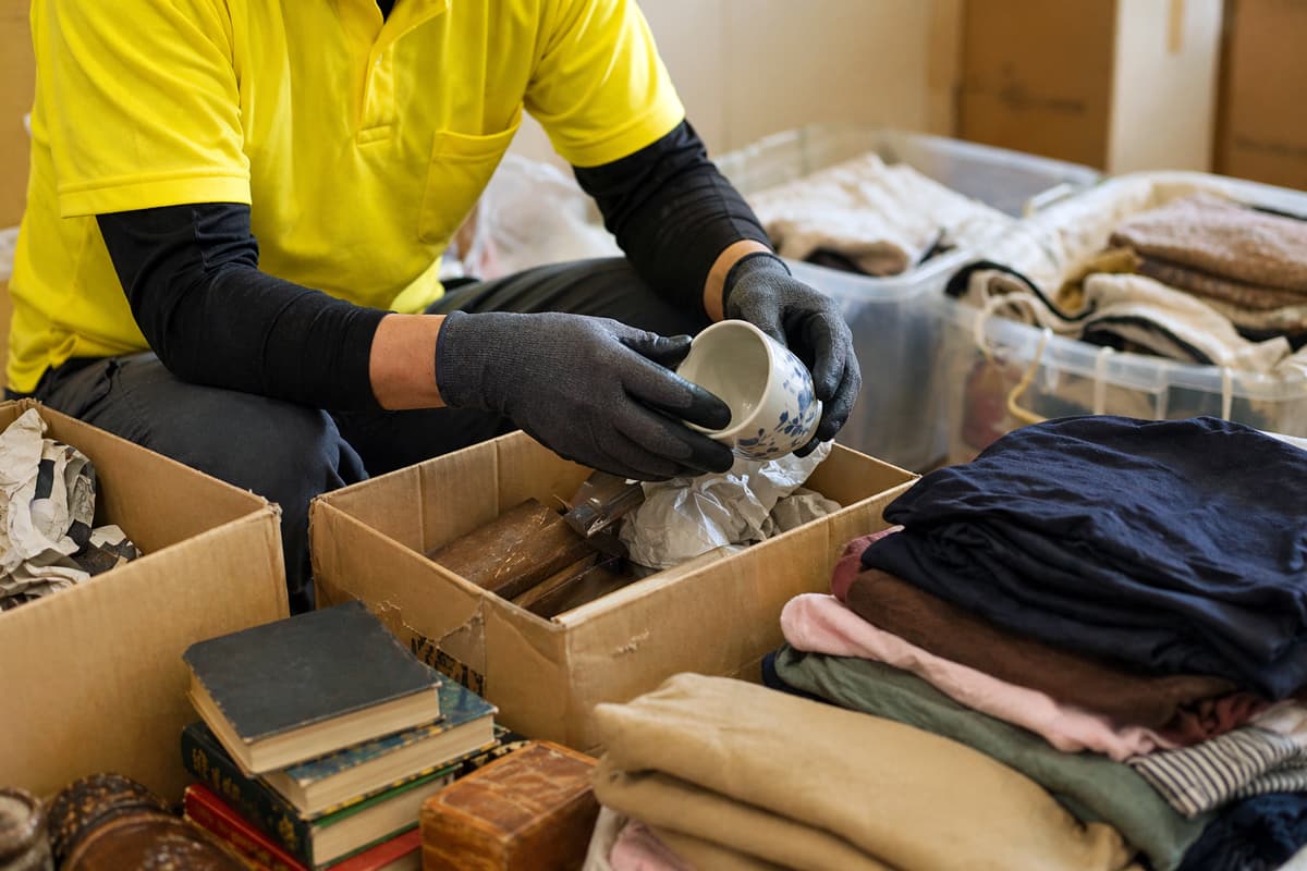 遺品整理の分別作業をイメージした画像。段ボール箱に食器類を仕分けしている様子