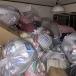 退去前のごみ屋敷状態の部屋に、袋詰めされたごみやダンボールが天井近くまで積み上がっている様子