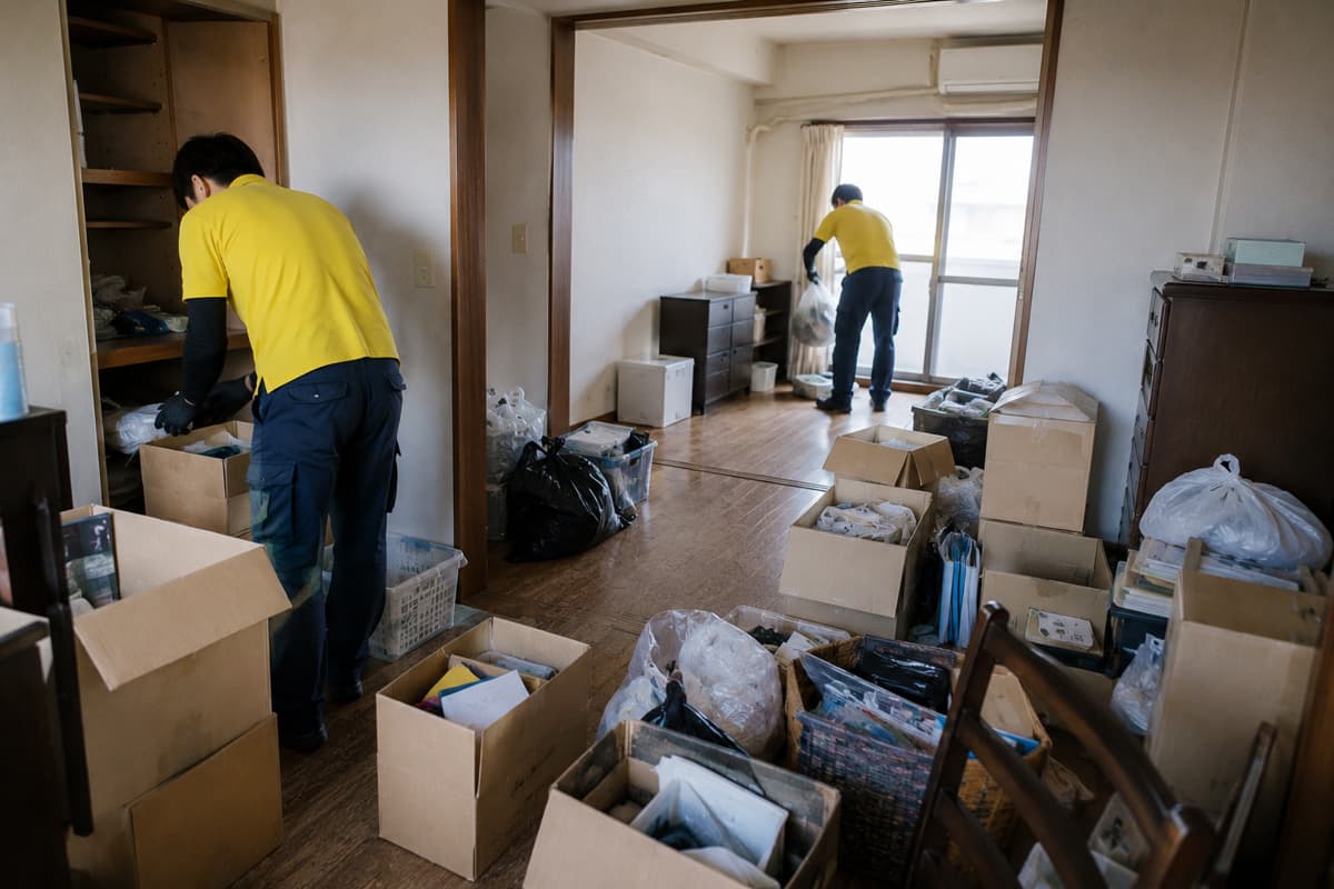 引越し後の住まいで不用品を仕分けしながら片付ける作業員