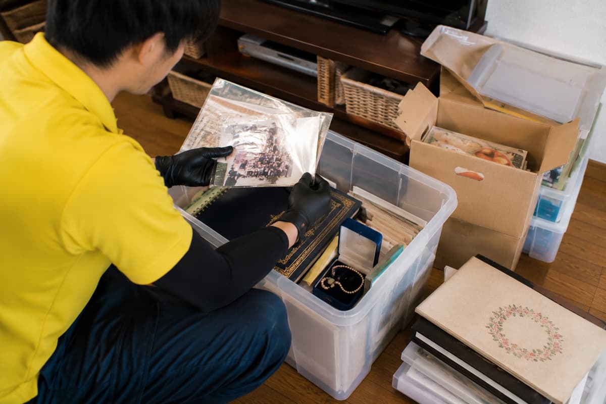 片付け中に見つかったアルバムや貴重品を慎重に確認する作業員