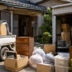 平屋の住宅と倉庫から運び出した家具や不用品をトラックへ積み込む片付け作業の様子