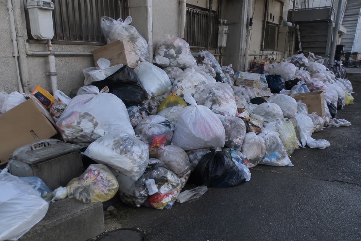片付け作業で室内から搬出され、建物の外に大量に集められたごみ袋や段ボールなどの不用品